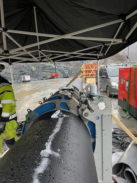 Rør sveises sammen med maskin under telt på anleggsområde.